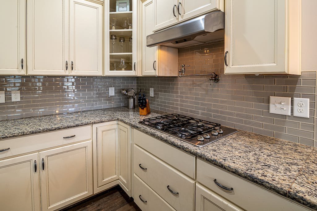 Stainless Steel Faucet Beside White Wooden Kitchen Cabinet